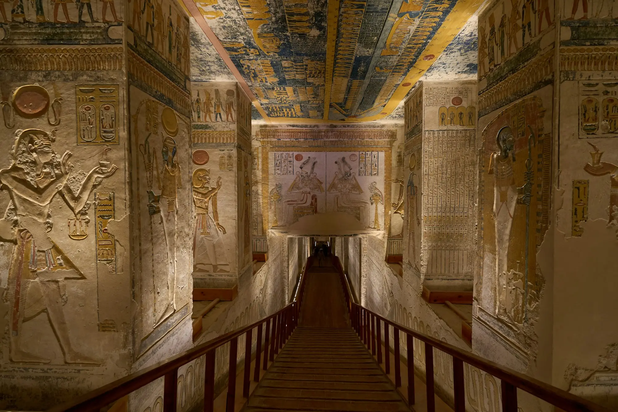 Painted corridor of tomb KV9 in the Valley of the Kings: colorful reliefs, a blue-and-gold ceiling and a descending walkway